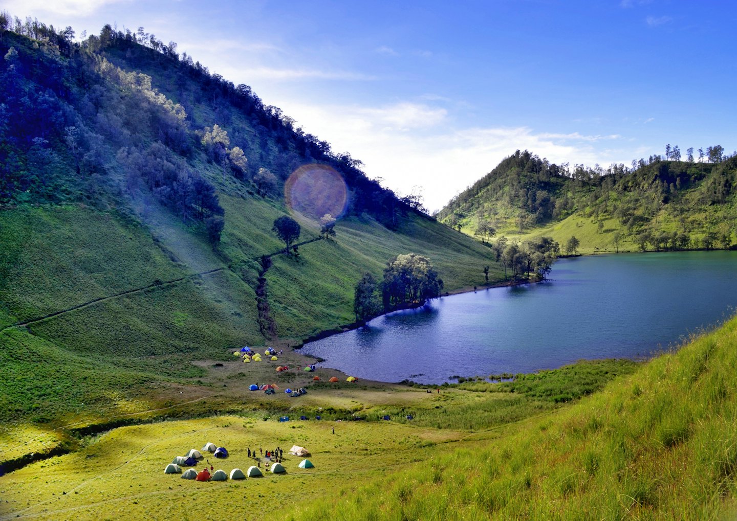 Colorful tents at a lakeside campsite with people.